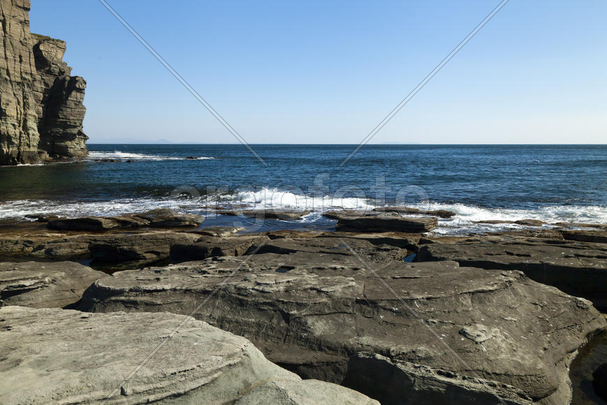 Rocks and sea meet in the bright sunlight in autumn