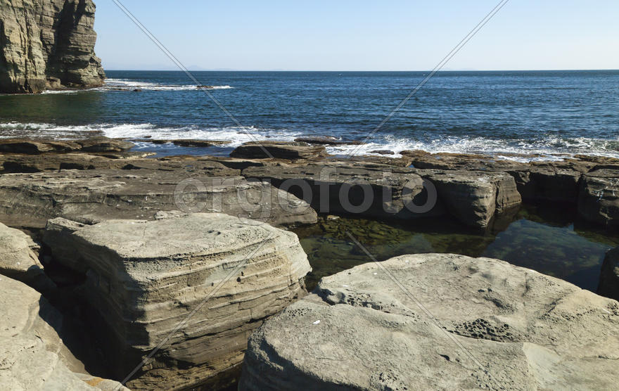 Rocks and sea meet in the bright sunlight in autumn