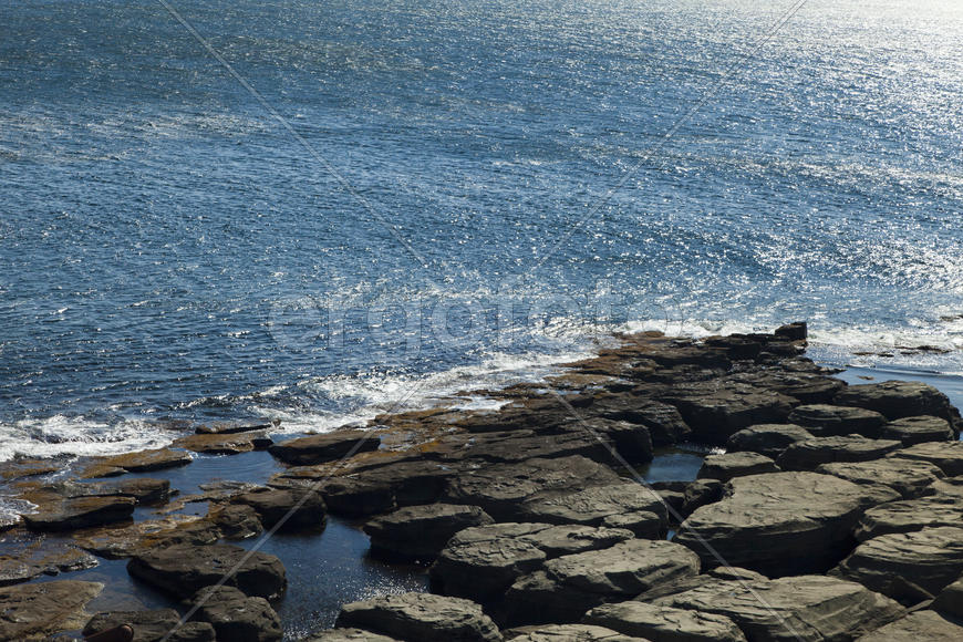 Rocks and sea meet in the bright sunlight in autumn