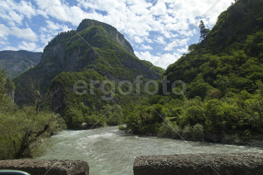 Mountains are covered with snow and the wood and surrounded with clouds