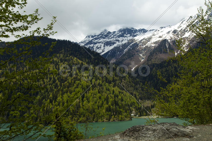 Mountains are covered with snow and the wood and surrounded with clouds