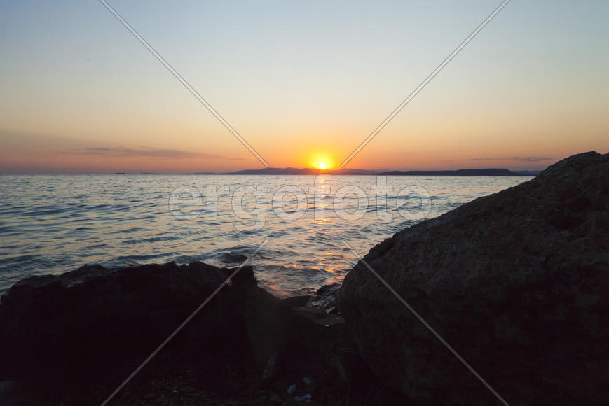 The sea at sunset in beams of the red setting sun