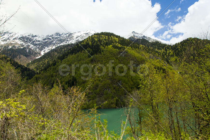 Mountains are covered with snow and the wood and surrounded with clouds