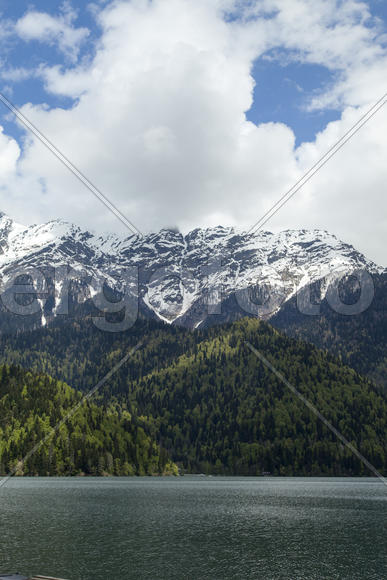 Mountains are covered with snow and the wood and surrounded with clouds