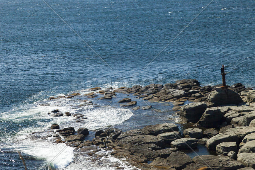 Rocks and sea meet in the bright sunlight in autumn