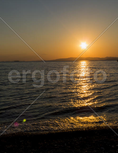 The sea at sunset in beams of the red setting sun