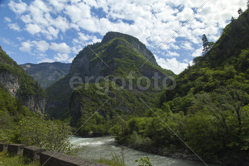 Mountains are covered with snow and the wood and surrounded with clouds