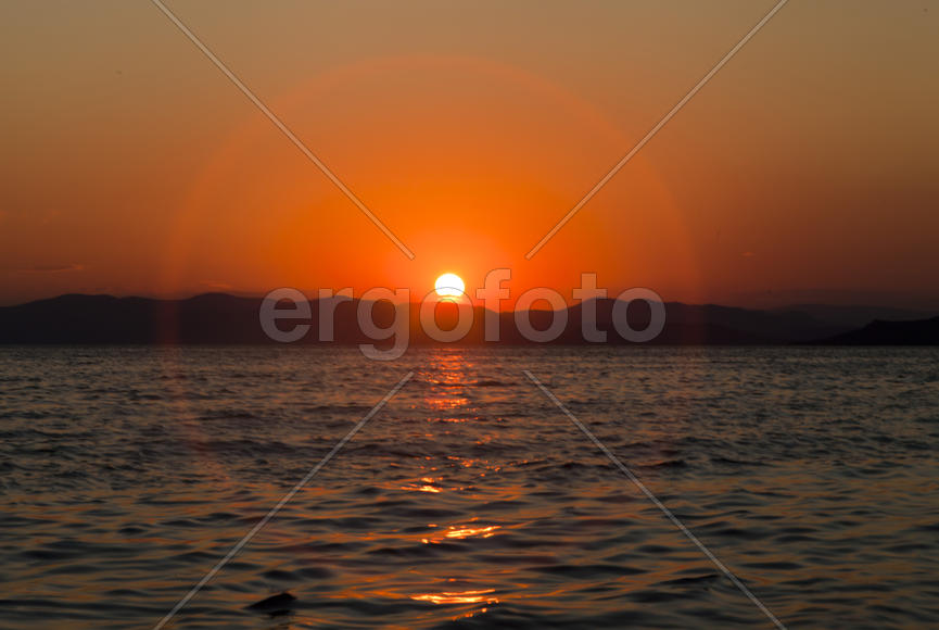 The sea at sunset in beams of the red setting sun