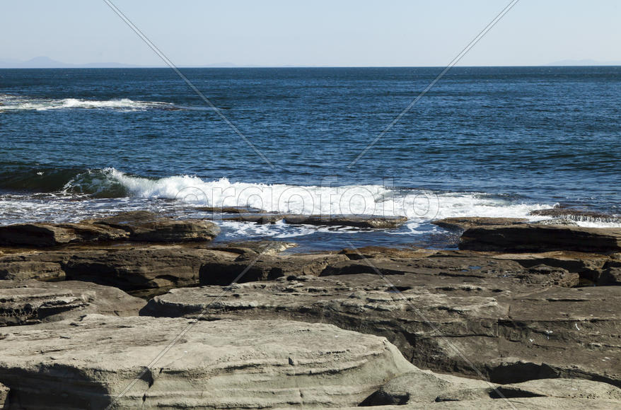 Rocks and sea meet in the bright sunlight in autumn
