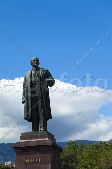 The monument to Lenin is among palm trees and against the bright blue sky