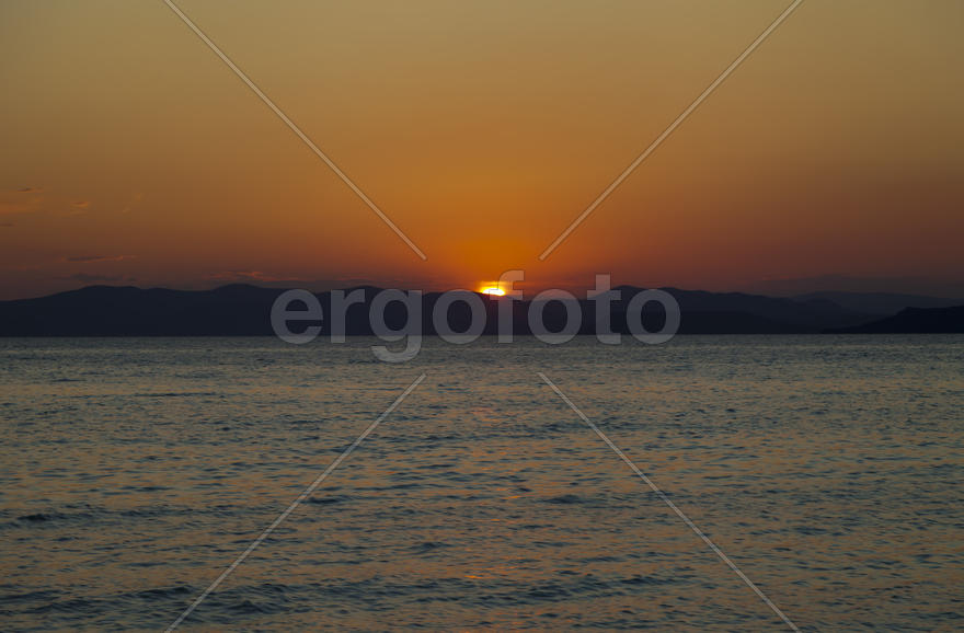 The sea at sunset in beams of the red setting sun