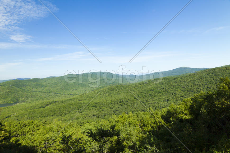 Green hills under the blue sky in beams of a bright sun