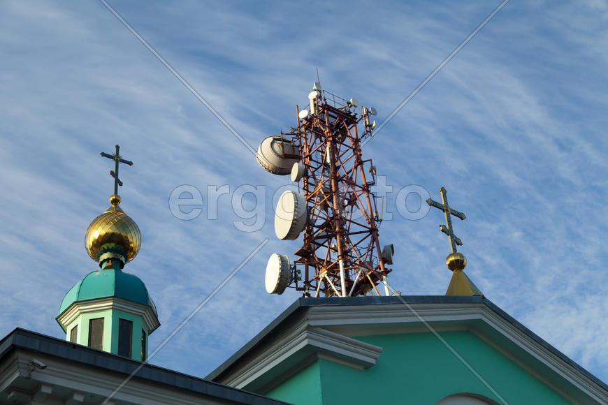 Communication tower against the bright blue sky with clouds