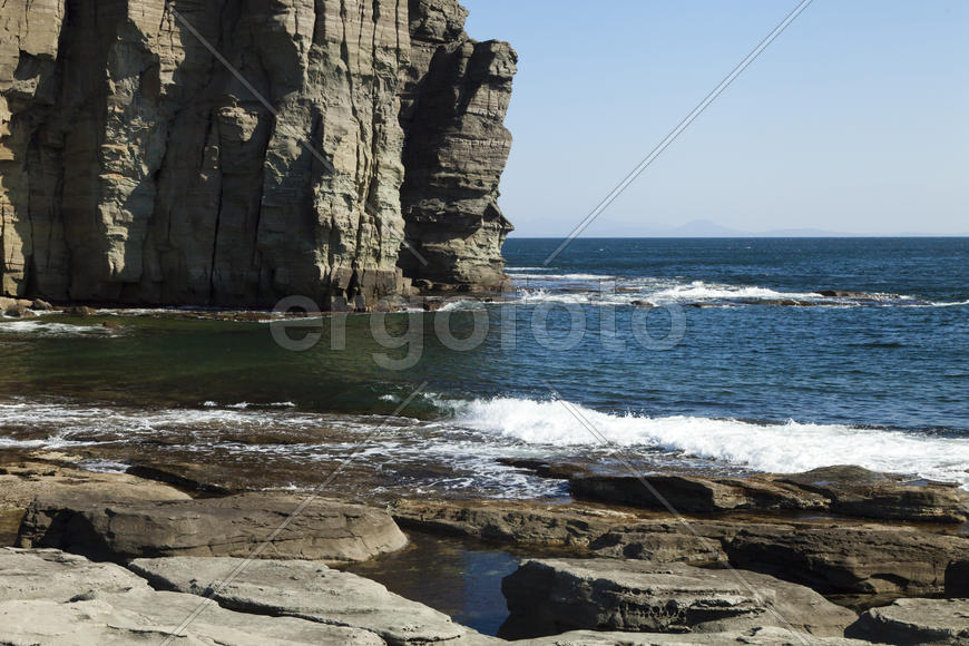 Rocks and sea meet in the bright sunlight in autumn