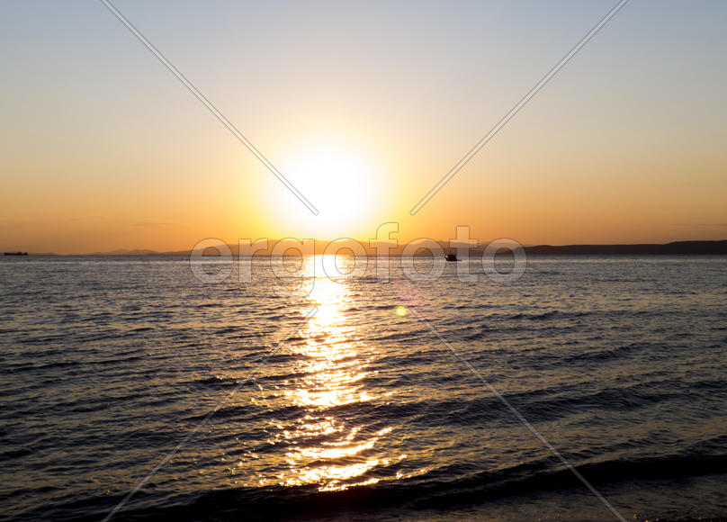 The sea at sunset in beams of the red setting sun