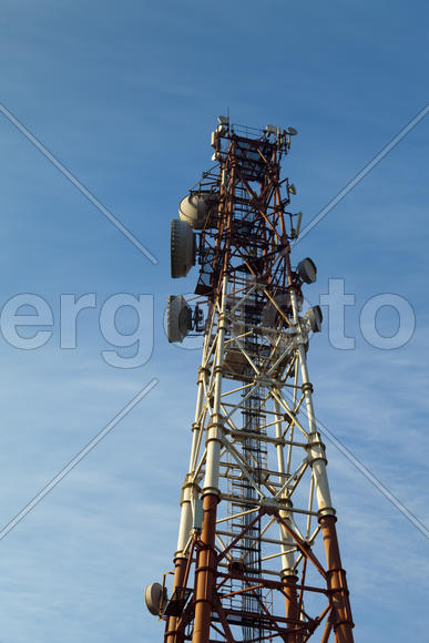 Communication tower against the bright blue sky with clouds