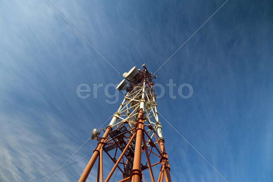 Communication tower against the bright blue sky with clouds
