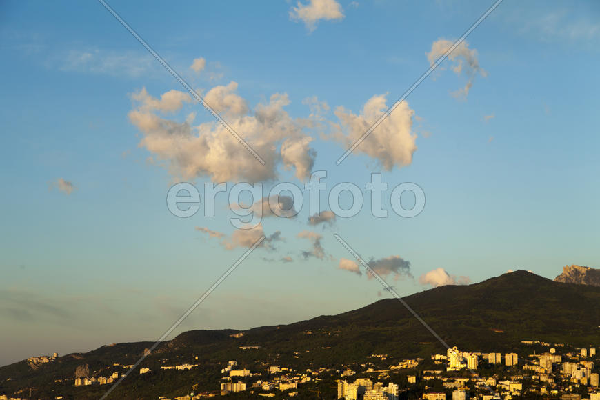 Mountains by the sea at sunrise in beams of the soft sun