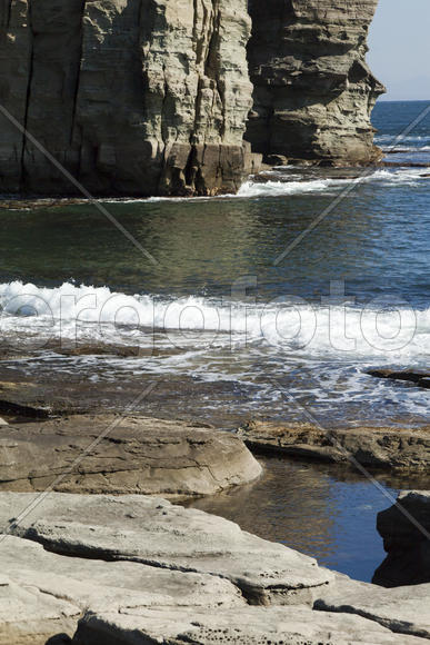 Rocks and sea meet in the bright sunlight in autumn