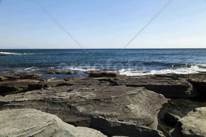Rocks and sea meet in the bright sunlight in autumn
