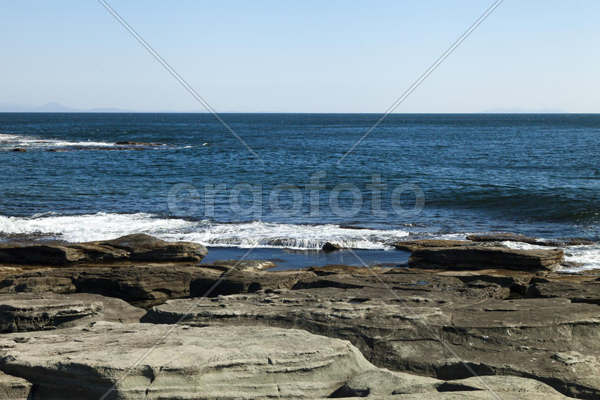 Rocks and sea meet in the bright sunlight in autumn