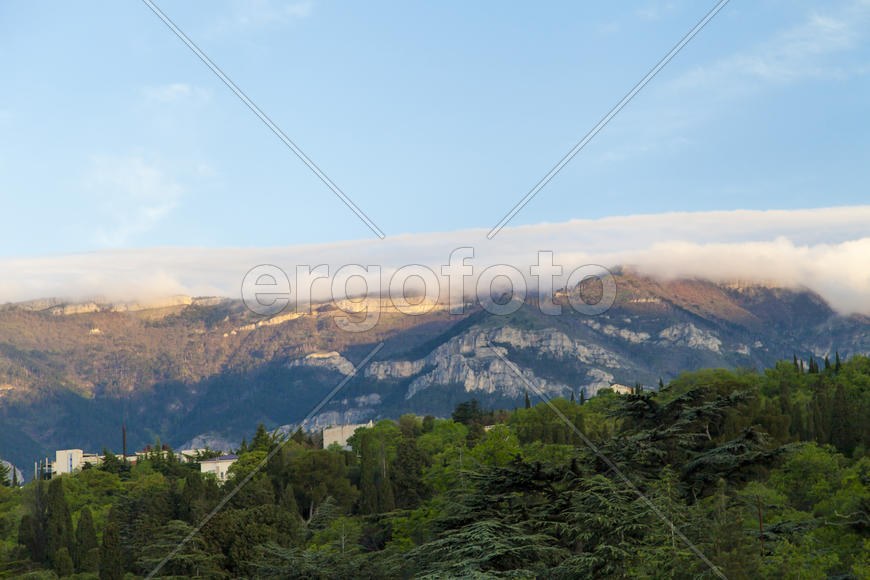 Mountains by the sea at sunrise in beams of the soft sun