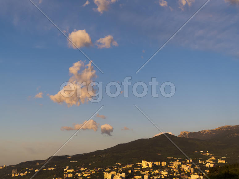 Mountains are covered with snow and the wood and surrounded with clouds