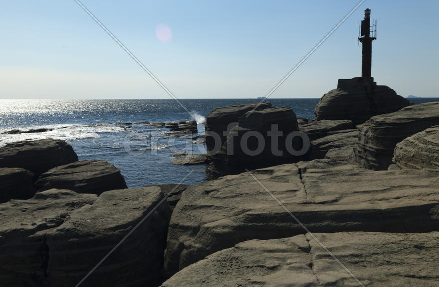 Rocks and sea meet in the bright sunlight in autumn