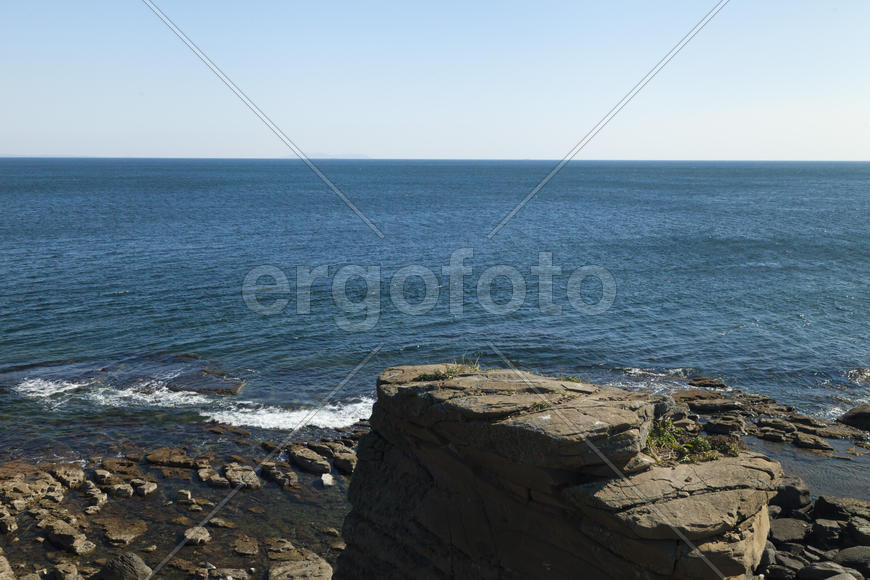 Rocks and sea meet in the bright sunlight in autumn