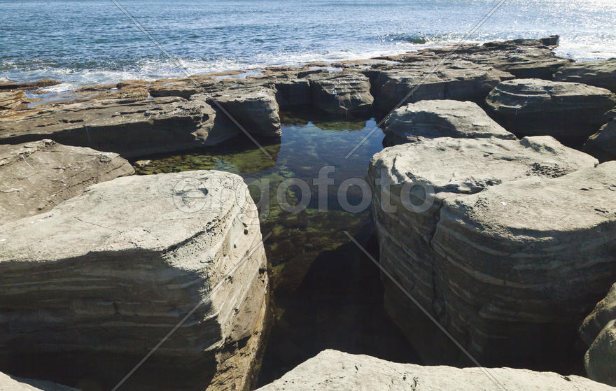 Rocks and sea meet in the bright sunlight in autumn