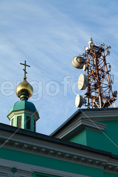 Communication tower against the bright blue sky with clouds