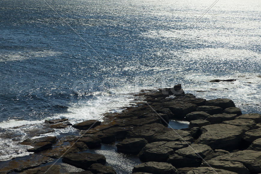 Rocks and sea meet in the bright sunlight in autumn