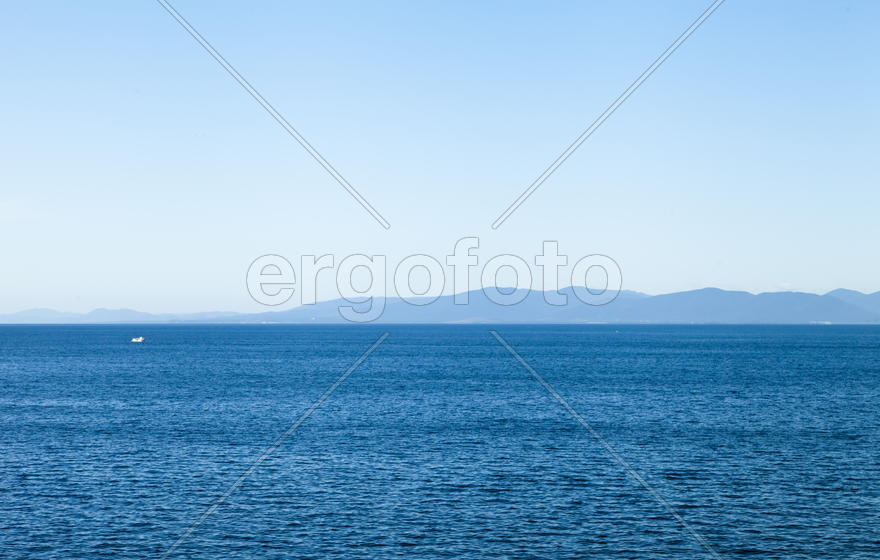 Seascape with ships and mountains on the horizon a bright sunny day