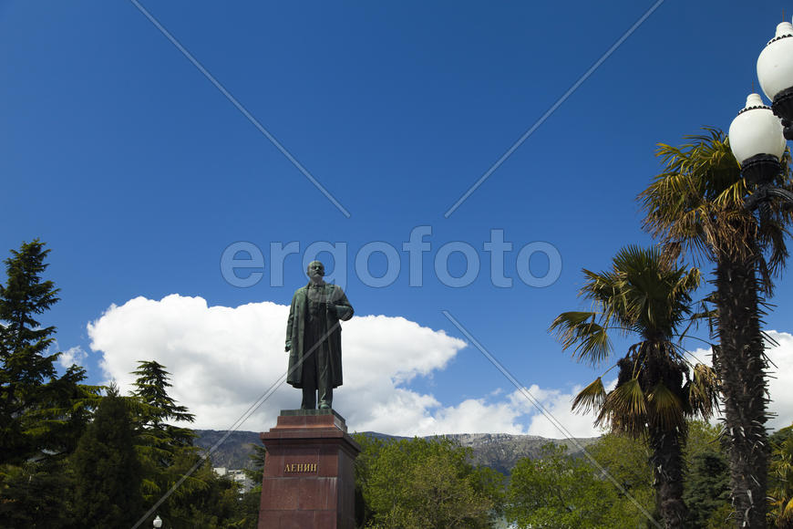 The monument to Lenin is among palm trees and against the bright blue sky