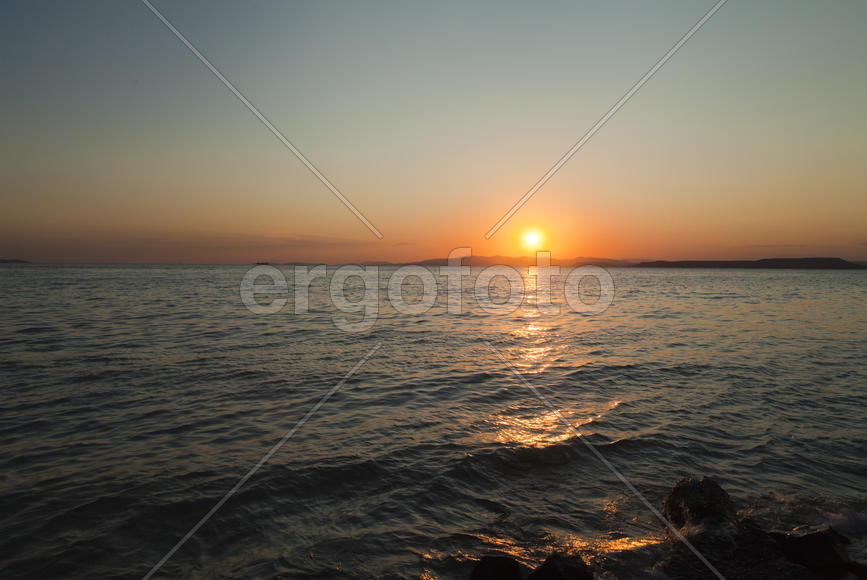 The sea at sunset in beams of the red setting sun