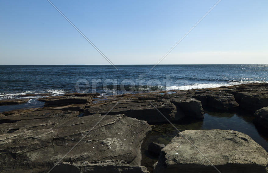 Rocks and sea meet in the bright sunlight in autumn