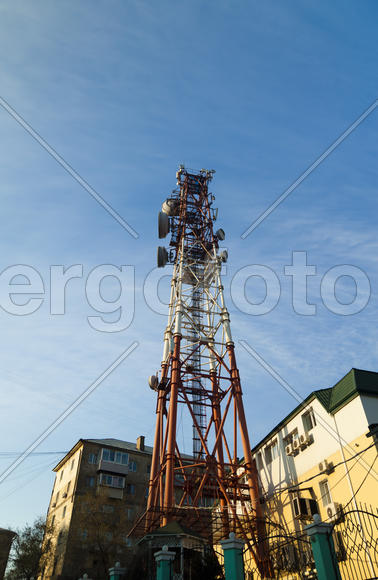 Communication tower against the bright blue sky with clouds