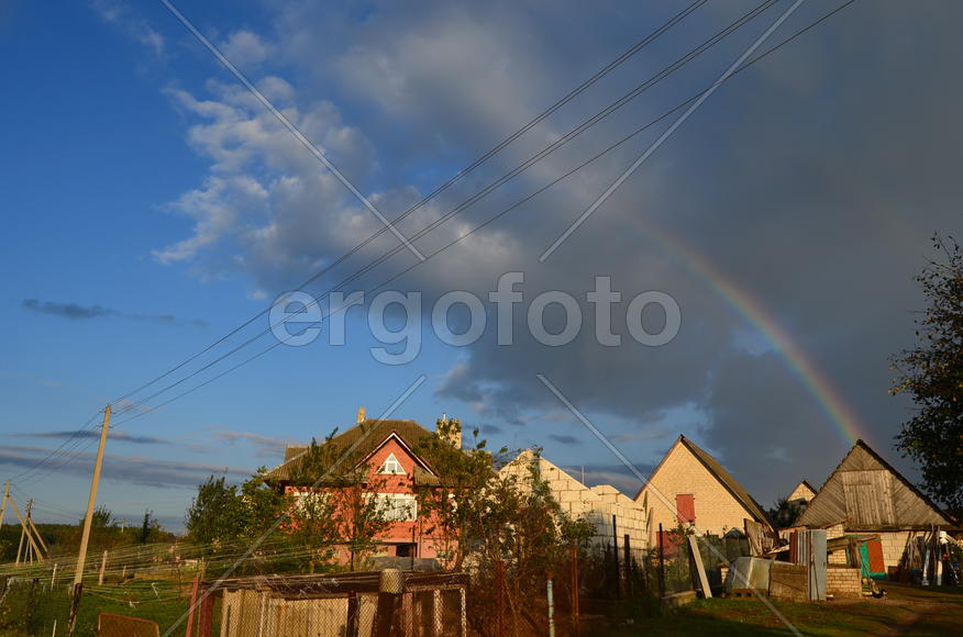 Радуга над деревней и частными домами 