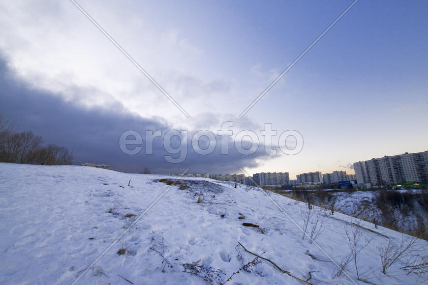 Холмы, снег, тучи и город