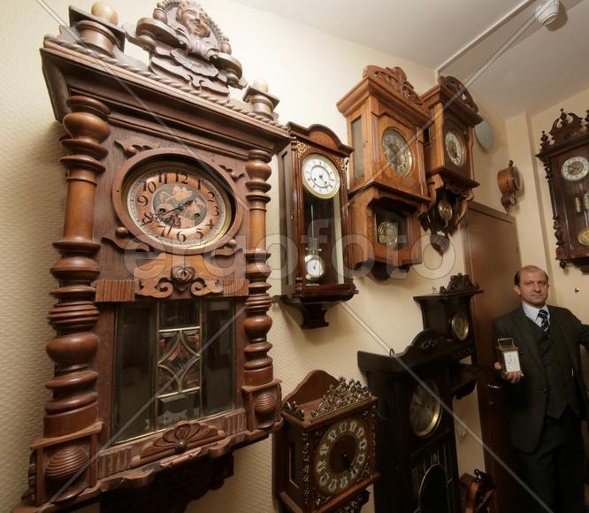 Коллекционер в окружении старинных механических часов 
