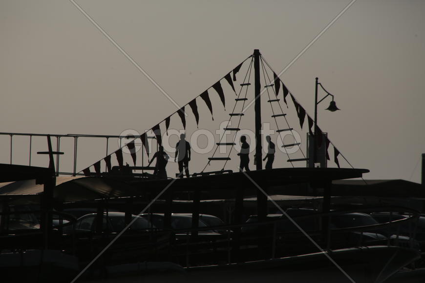 Силуэты людей, на крыше украшенной канатными лестницами и флажками. Ливан 