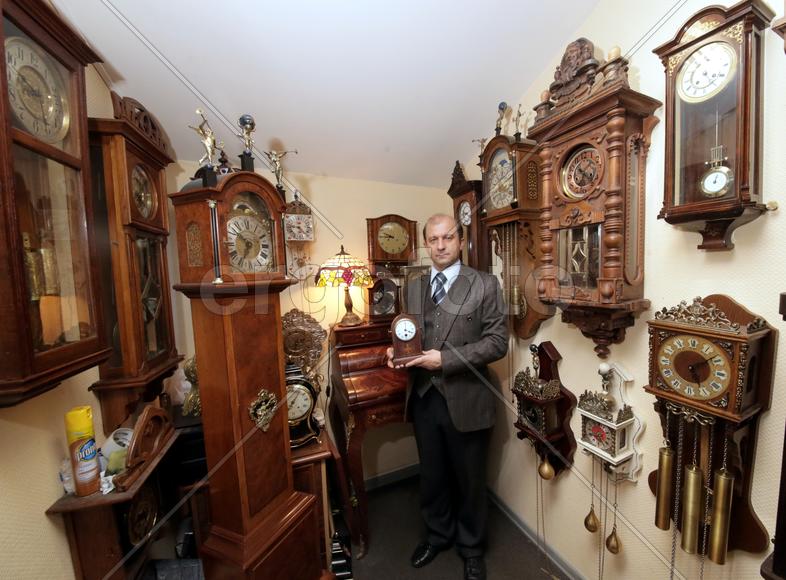 Коллекционер в окружении старинных механических часов 