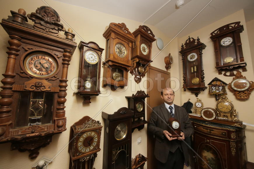 Коллекционер в окружении старинных механических часов 