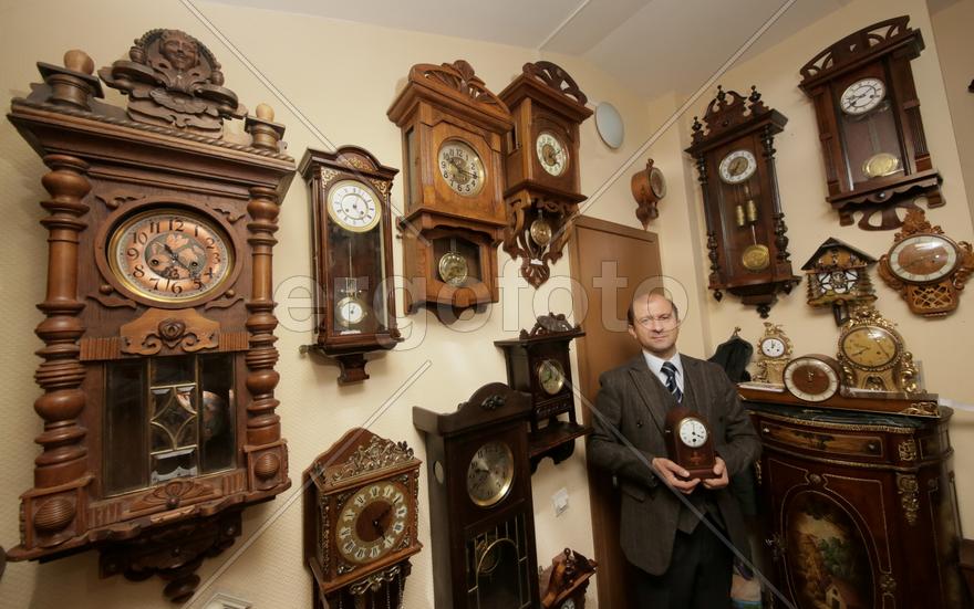 Коллекционер в окружении старинных механических часов 