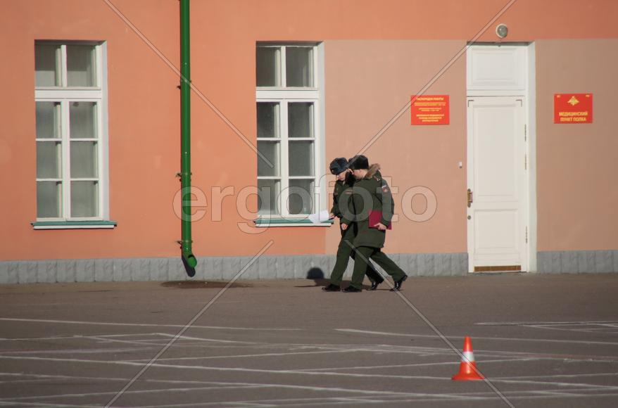Военные идут вдоль здания 