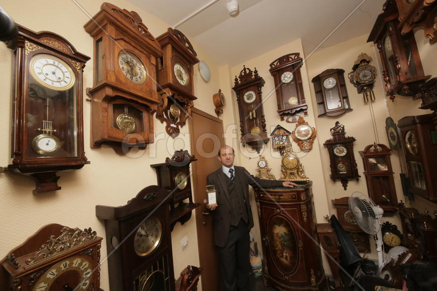 Коллекционер в окружении старинных механических часов 