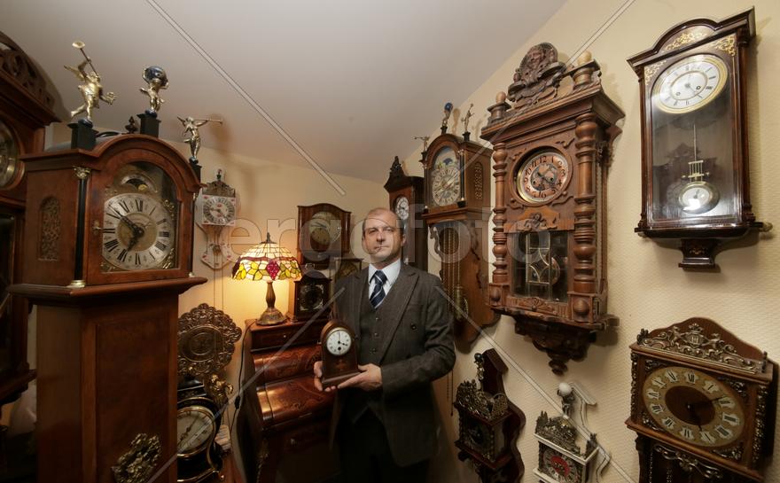 Коллекционер в окружении старинных механических часов 