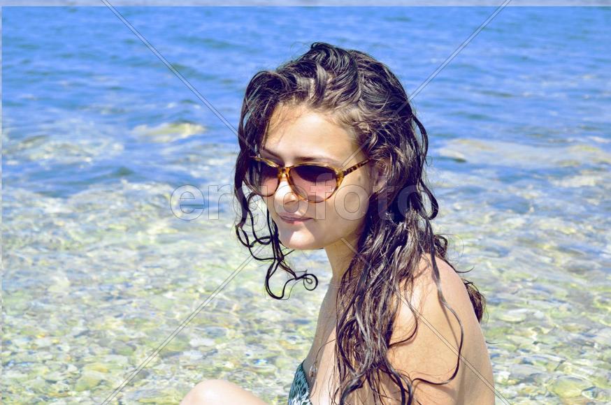 Девушка с темными волосами в очках на море
