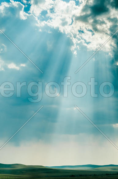 Ярко голубые облака на небе над зеленым лугом 