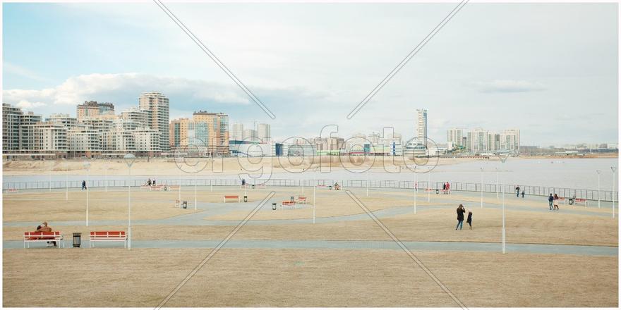 Люди гуляют парку на фоне высотных домов.